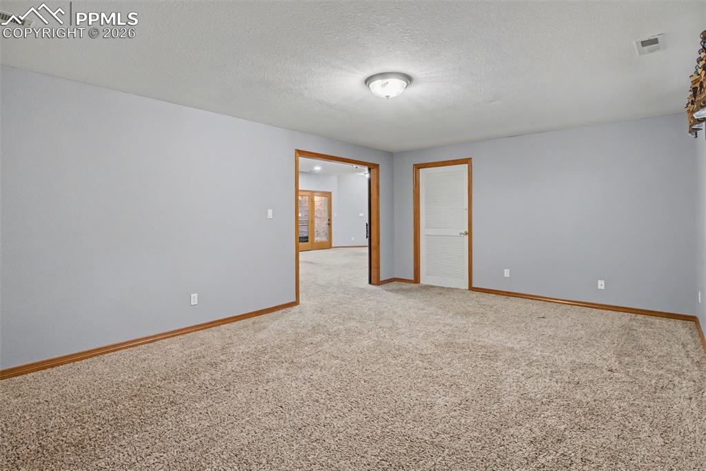 Unfurnished room with a textured ceiling and light colored carpet