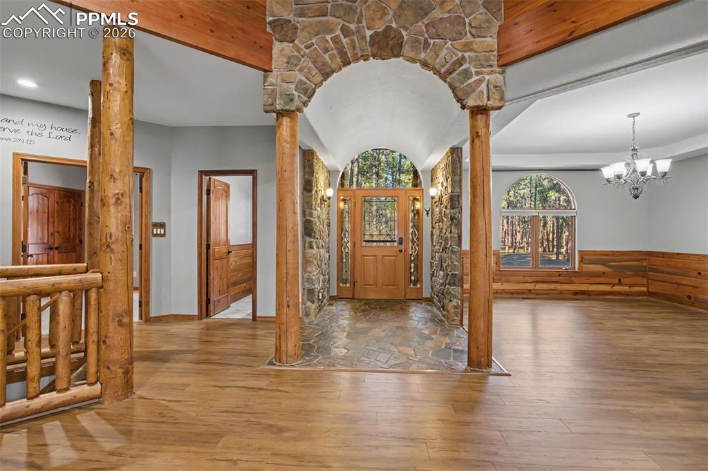 Entryway featuring hardwood / wood-style floors, ornate columns, a chandelier, and arched walkways