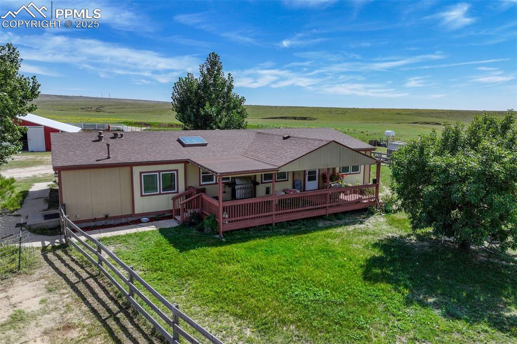 Back of property featuring a shingled roof, a rural view, and a wooden deck