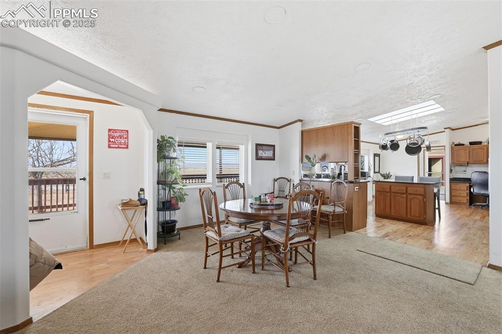 Dining room featuring light wood-style flooring, crown molding, and a textured ceiling