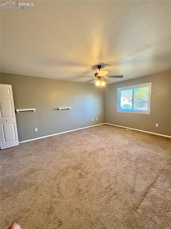 Unfurnished room featuring carpet, a textured ceiling, and a ceiling fan