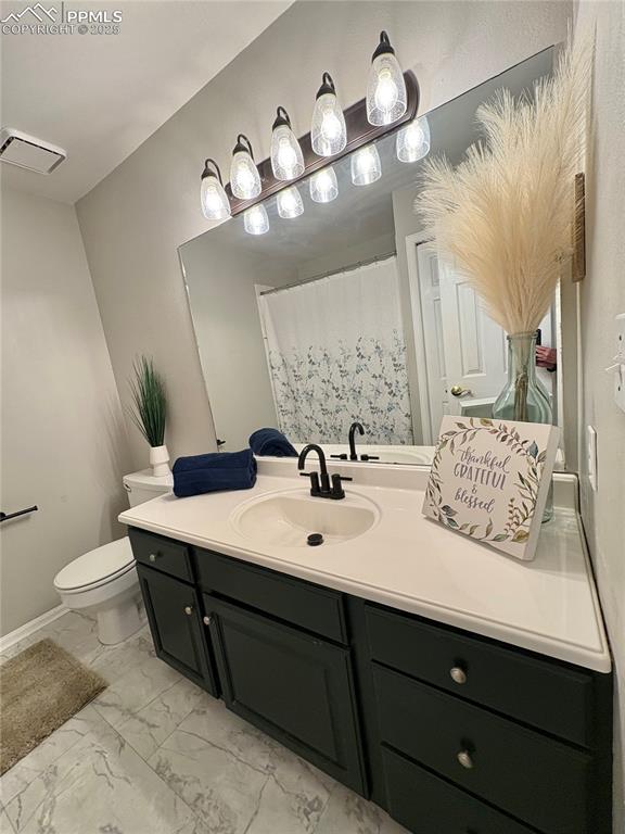 Full bath with vanity, light marble finish floors, and a shower with curtain