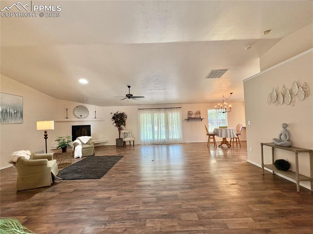 Living room featuring a ceiling fan, dark wood-style flooring, a chandelier, recessed lighting, and lofted ceiling
