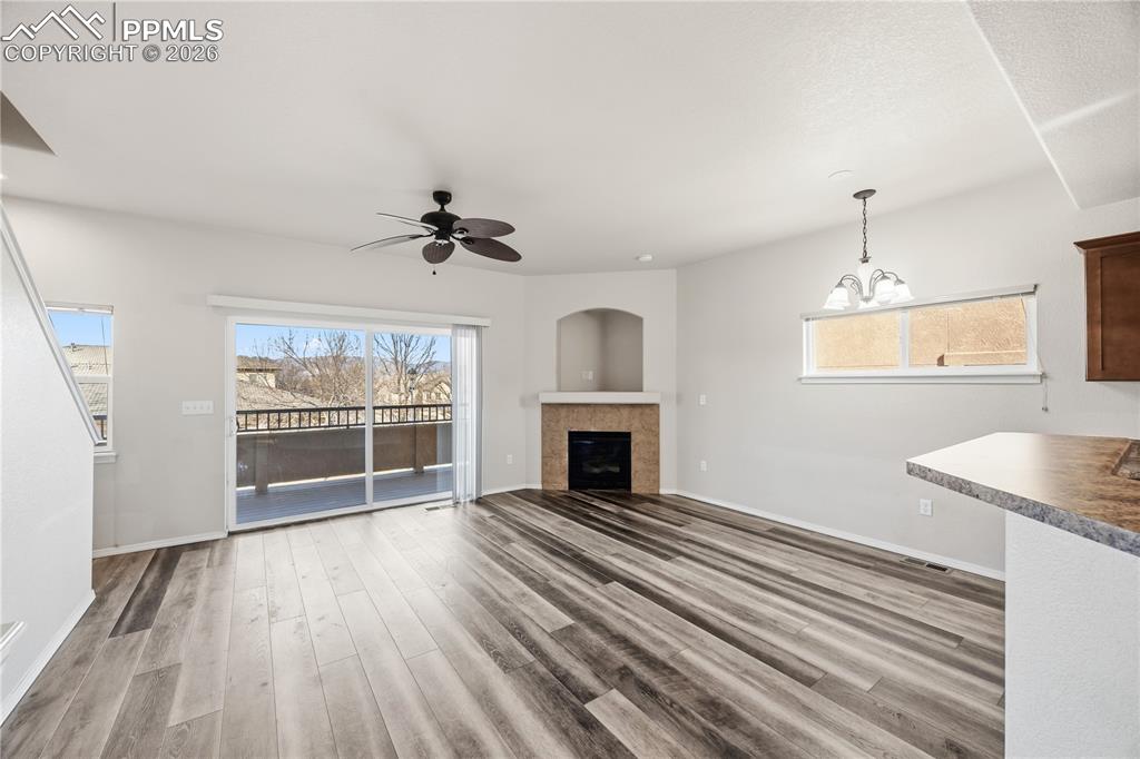 The Living Room features a ceiling fan, LVP flooring, a gas fireplace with time surround, art niche, and sliding door to a private baclony.