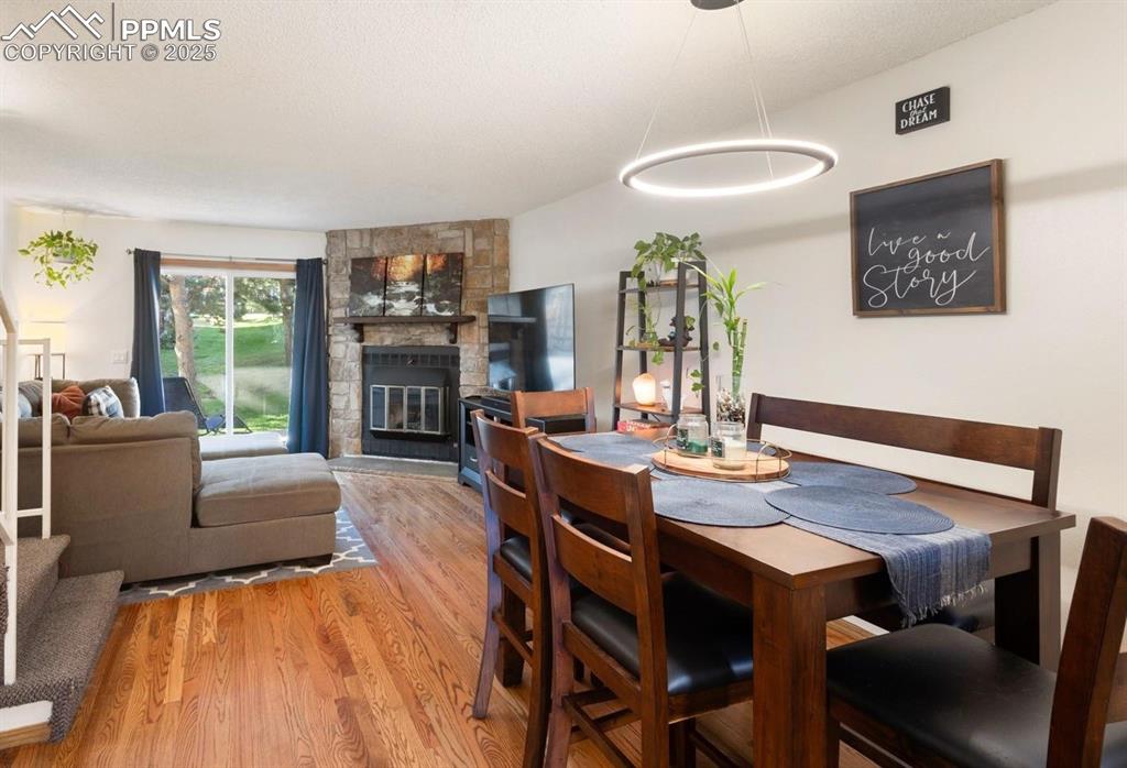 Dining space with wood finished floors, a fireplace, and a textured ceiling