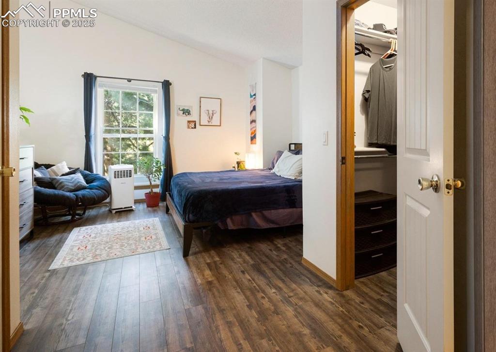 Bedroom with dark wood-type flooring and lofted ceiling
