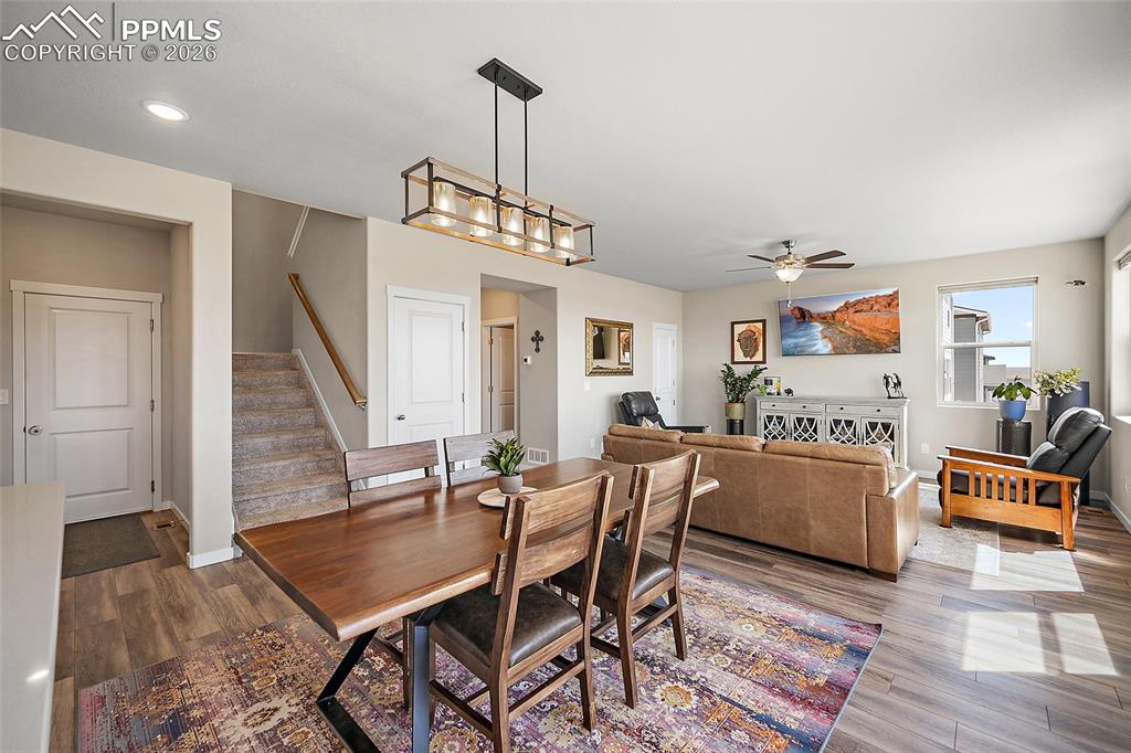 Dining area with view of mudroom leading to garage, stairs leading to upper level, stairs leading to lower level, and living room