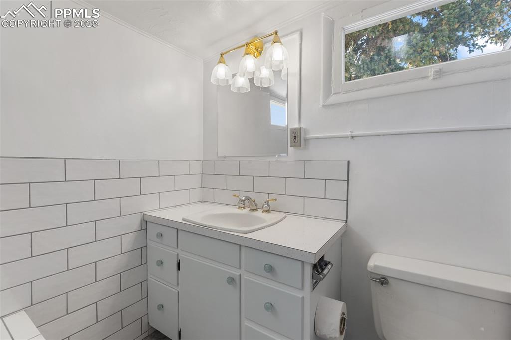 Half bath featuring vanity, tile walls, and crown molding