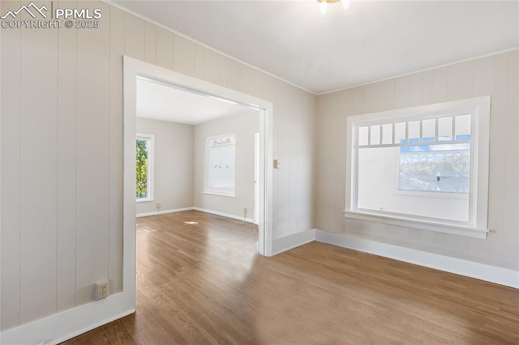 Unfurnished room featuring wood finished floors, plenty of natural light, and crown molding