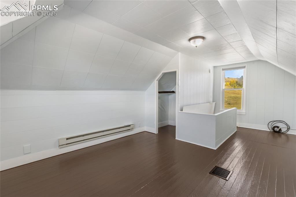 Bonus room with dark wood-style flooring, a baseboard radiator, and lofted ceiling