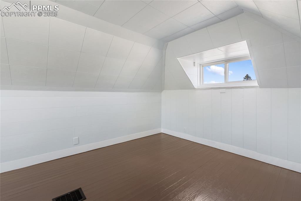 Additional living space with lofted ceiling and dark wood-style floors