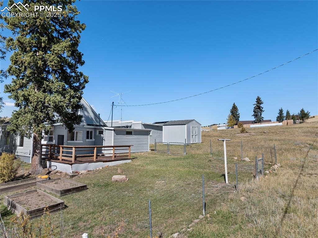 View of yard featuring a wooden deck, a vegetable garden, and a shed