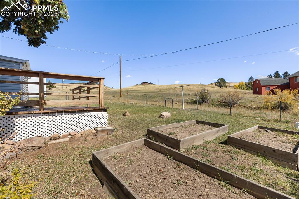 View of yard featuring a view of rural / pastoral area, a deck, and a vegetable garden