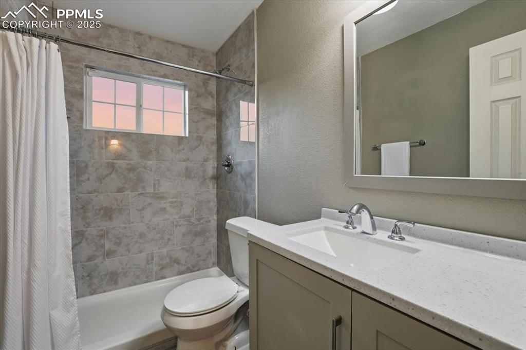 Full bathroom with a textured wall, vanity, and tiled shower