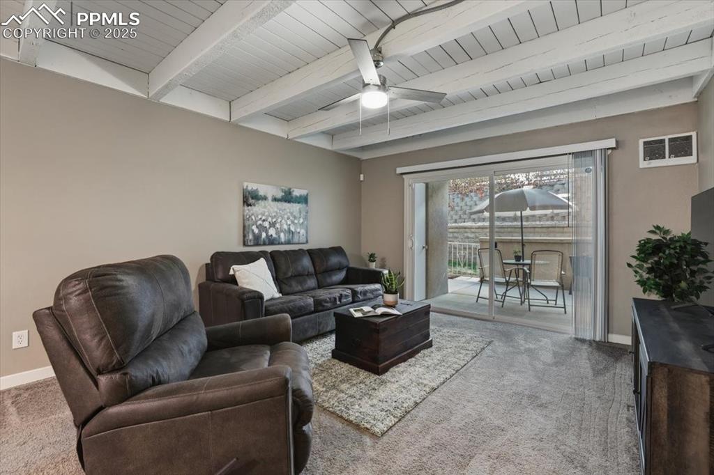 Living area featuring beamed ceiling, light carpet, and ceiling fan