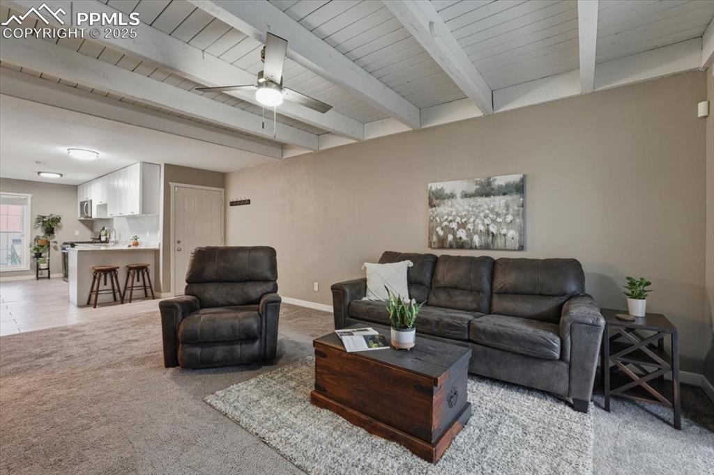 Living room with light carpet, beamed ceiling, and ceiling fan