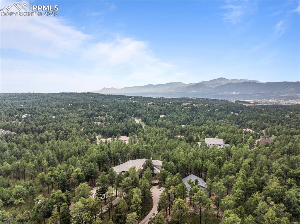 Bird's eye view of the home, nestled in the trees with views of the mountains
