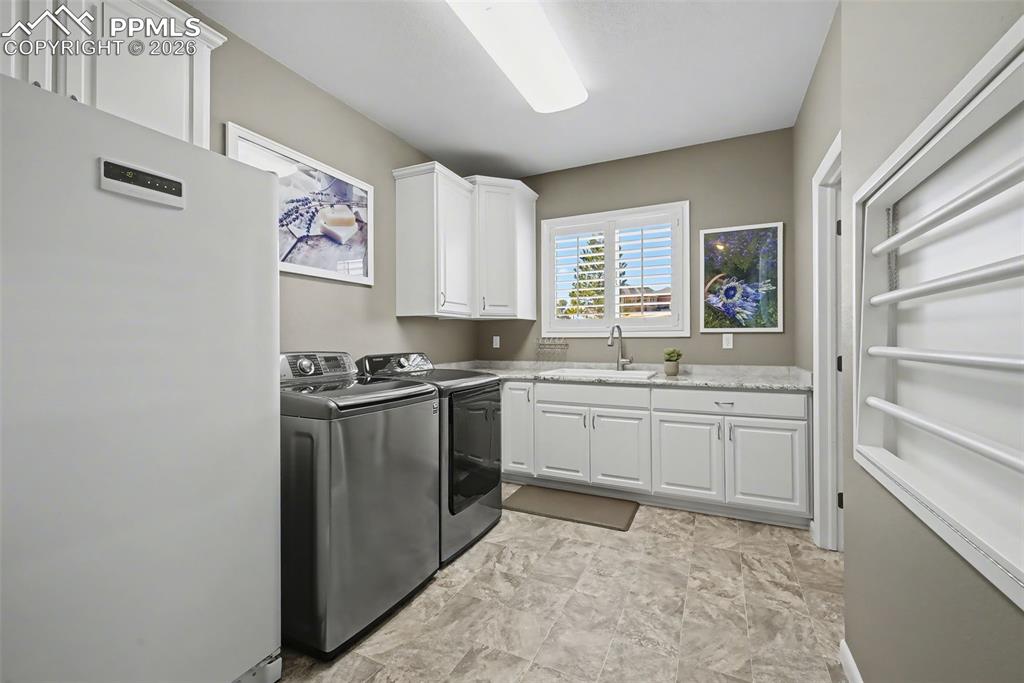 Expansive laundry room with stand-up freezer, drying racks sink and pantry access