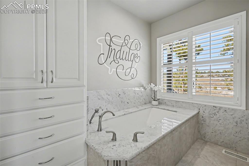 Large and insulated soaking tub with walk in shower to the right.