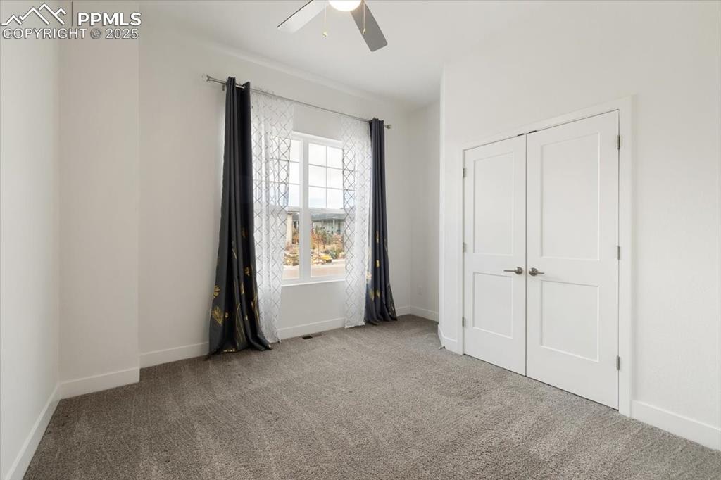 Unfurnished bedroom featuring carpet floors, baseboards, a ceiling fan, and a closet