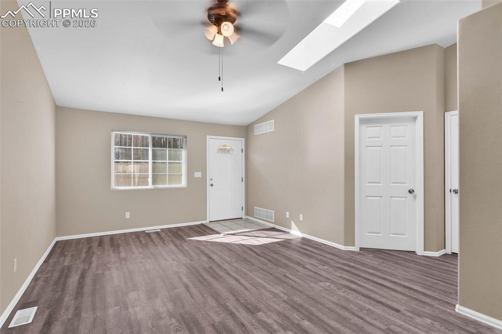 Entryway featuring a skylight, vaulted ceiling, a ceiling fan, and dark wood-type flooring