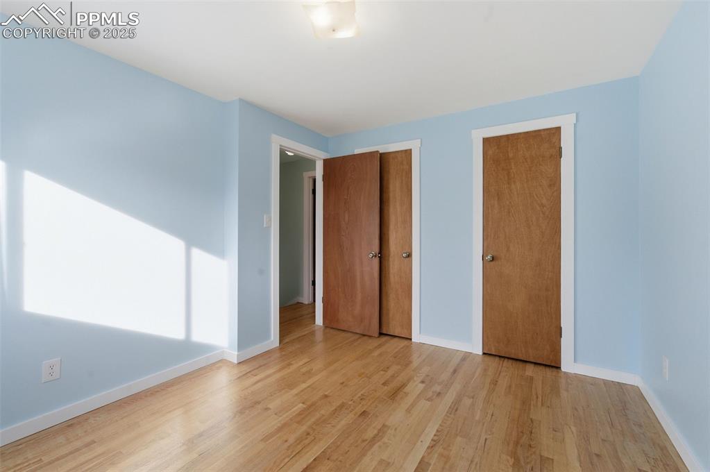 Unfurnished bedroom featuring two closets and wood finished floors