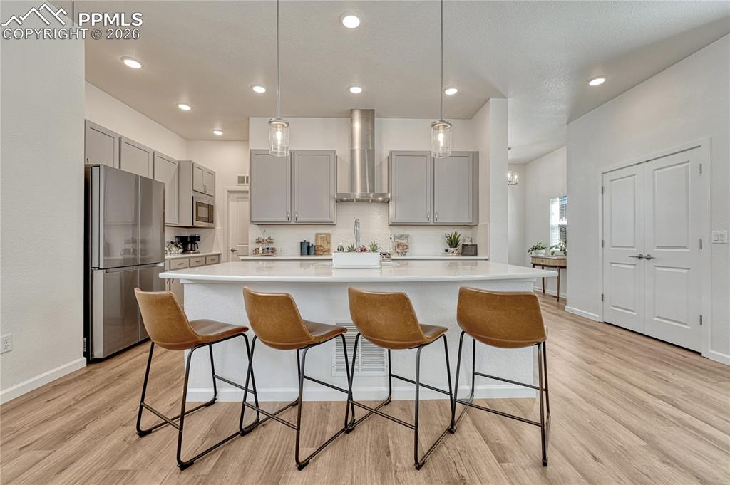 The kitchen has a large island with breakfast bar and solid white quartz countertops
