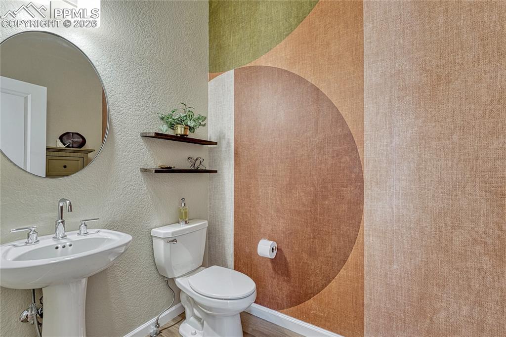 Just past the stairs is a large half bath/powder room with a stylistic wallpapered accent wall