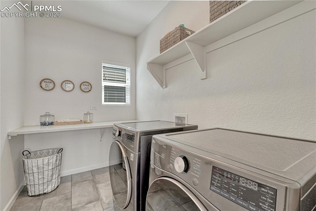 This laundry space has room for large washer/dryer units along with storage shelves and folding counter
