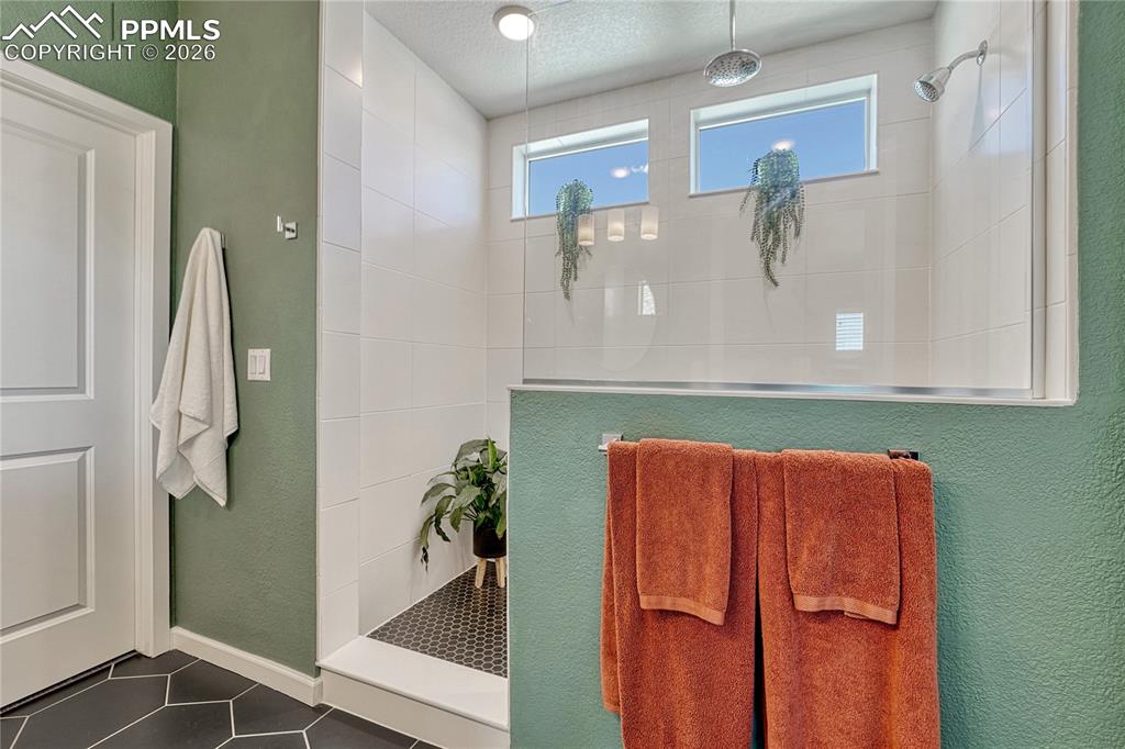 A large glass half wall for the shower keeps the space feeling open while showing off the clean whistle tile and rain style shower head
