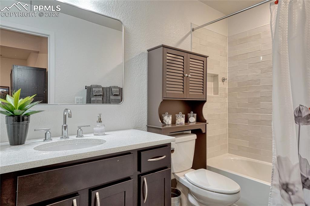 The basement level full bathroom has the same sparkling white counters and shower/tub tile surround
