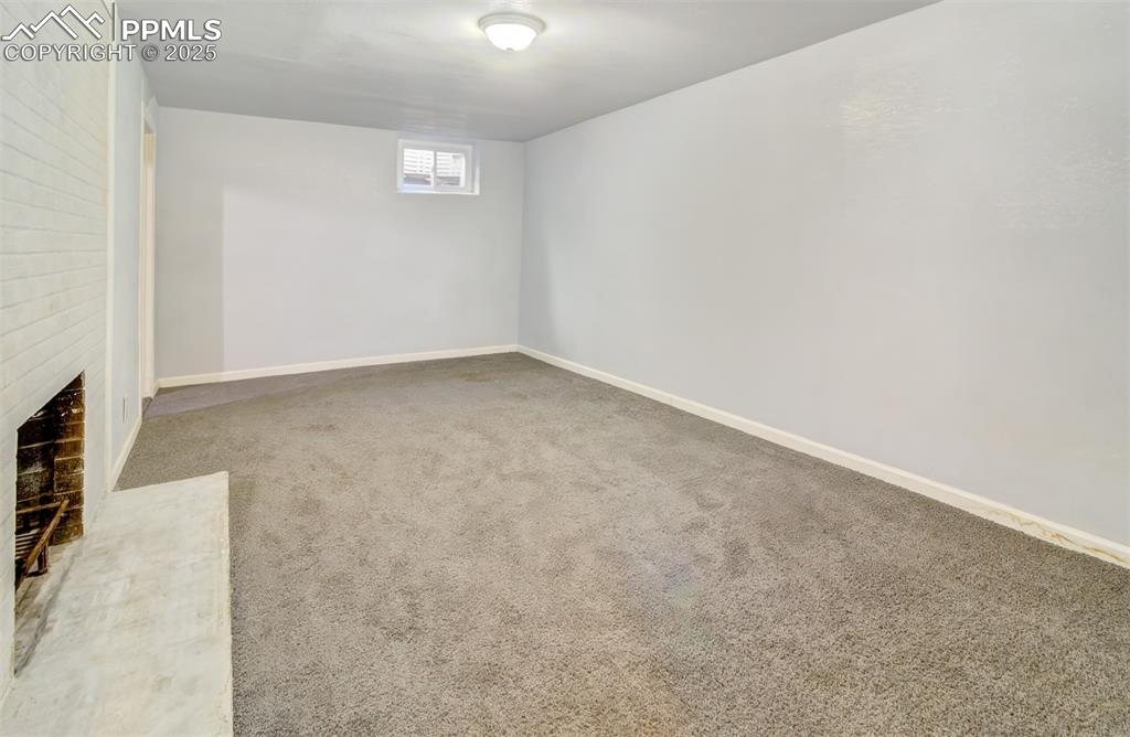 Below grade area with a brick fireplace, carpet, and baseboards