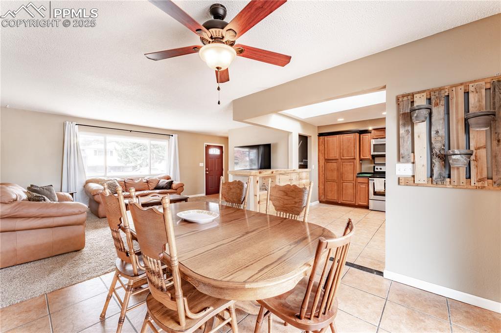 Dining space featuring light tile patterned flooring, a ceiling fan, and a textured ceiling
