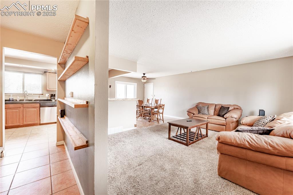 Living area featuring a textured ceiling, light carpet, and light tile patterned floors