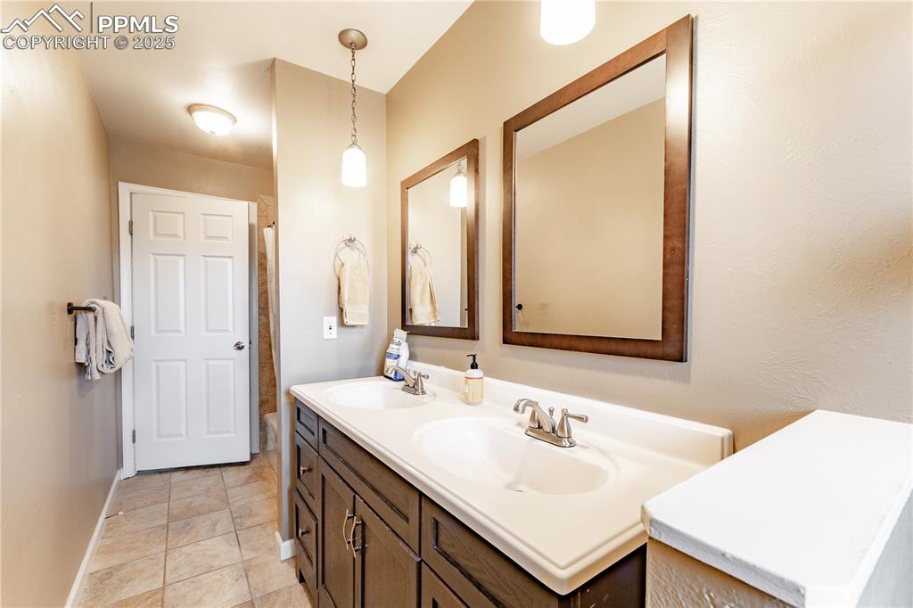 Full bath with double vanity and light tile patterned flooring