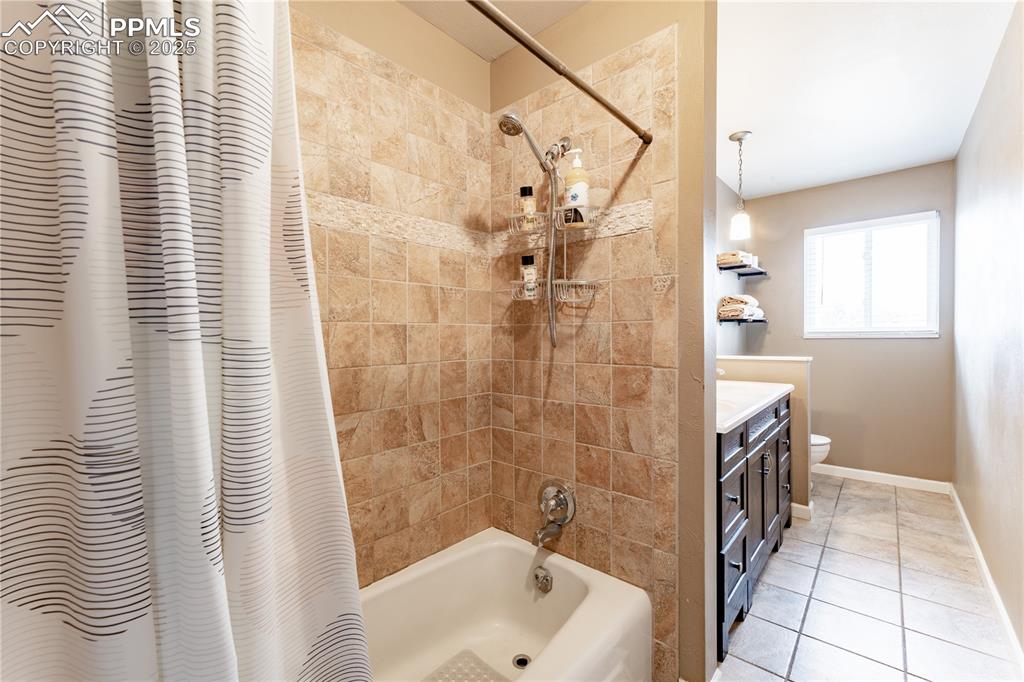 Bathroom featuring vanity, shower / bath combo, and light tile patterned floors