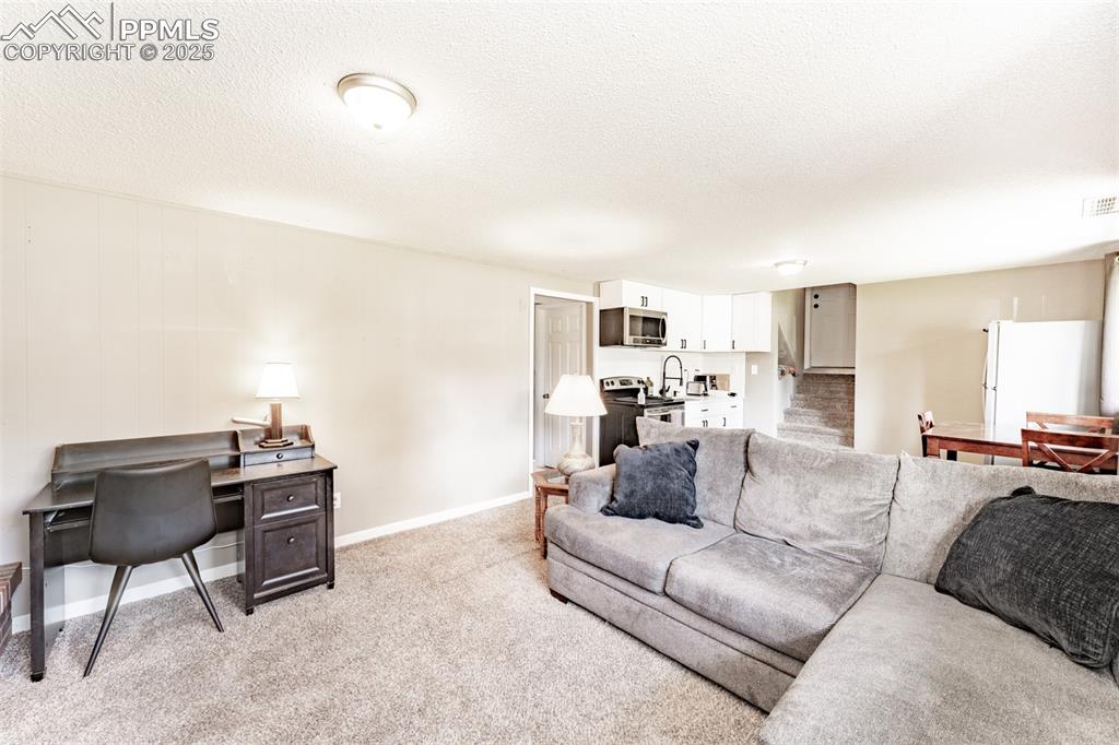 Living room featuring a textured ceiling, light colored carpet, and an office area