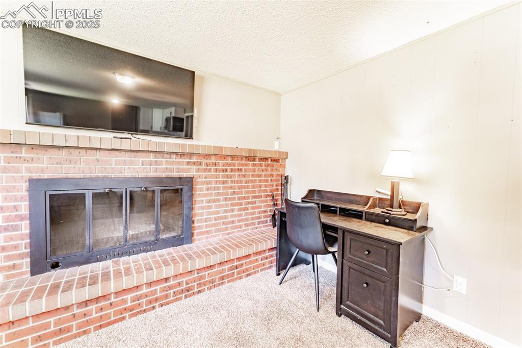 Carpeted office space with a fireplace and a textured ceiling