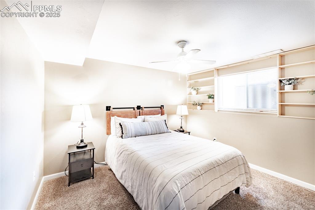 Carpeted bedroom with ceiling fan and baseboards