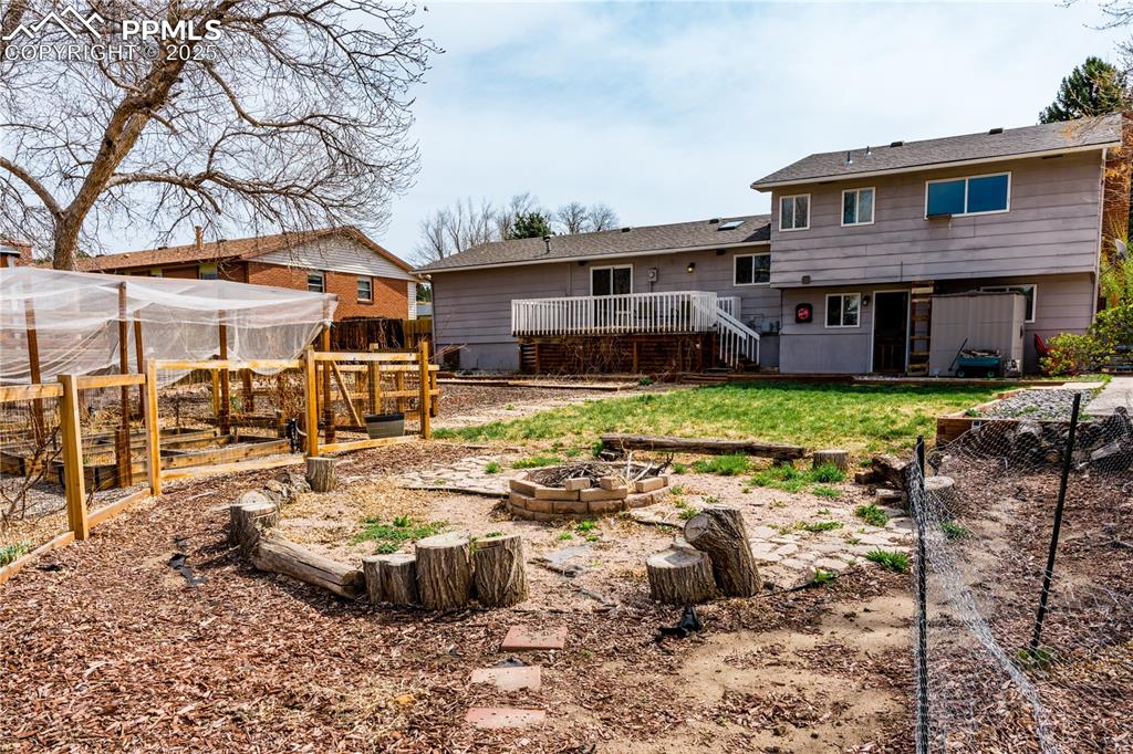Rear view of property with a deck, a garden, an outdoor fire pit, stairway, and an outbuilding