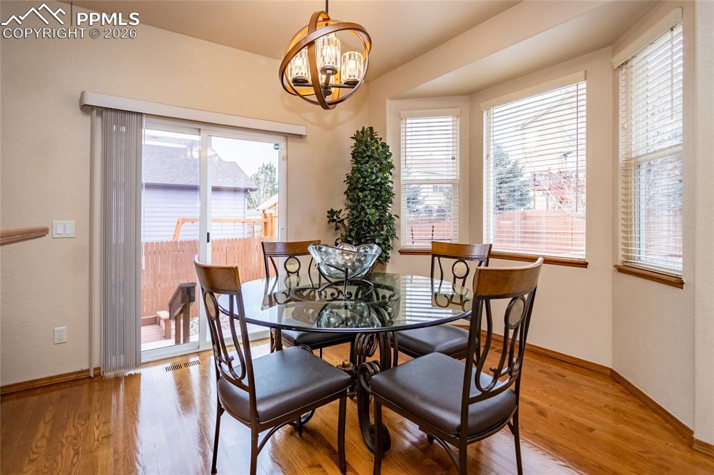 Breakfast nook with hardwood flooring and a bay window walks out to the deck.