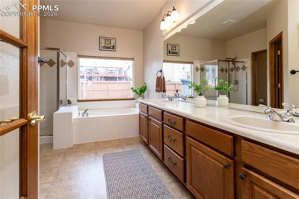 Adjoining primary bathroom is separated with a glass door.