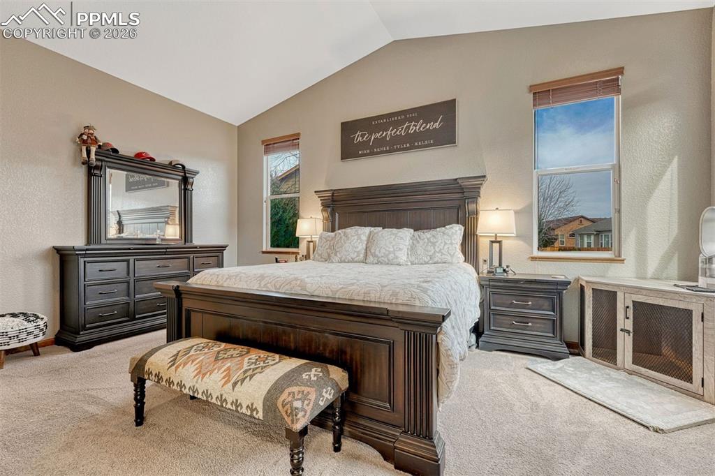 Bedroom with carpet, vaulted ceiling, and  textured walls