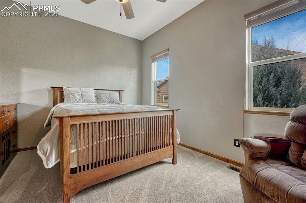 2nd main level Bedroom with light colored carpet, a textured wall, and a ceiling fan