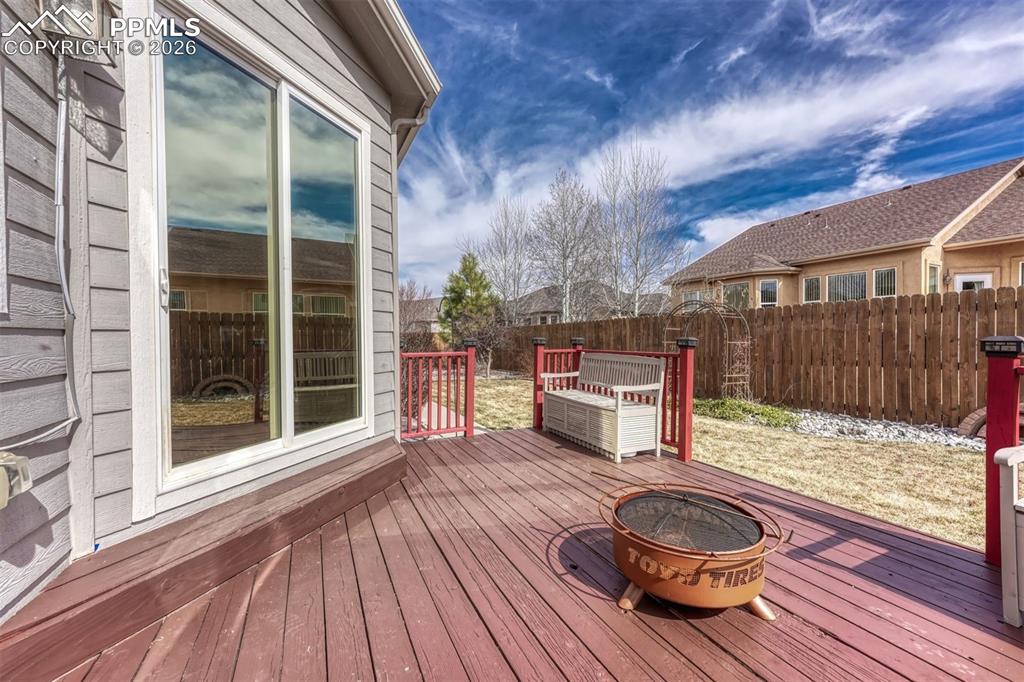 Deck with an outdoor fire pit and a fenced backyard