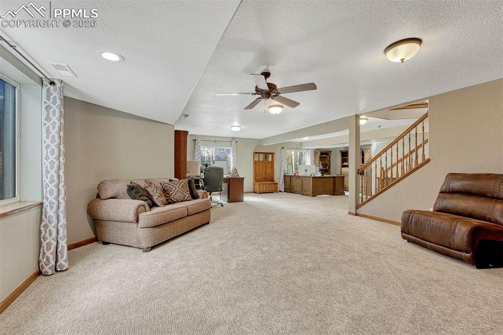 Living area featuring a ceiling fan, light carpet, and a textured ceiling