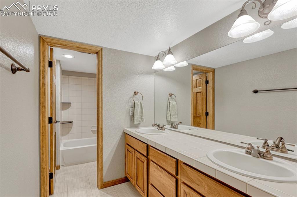 Basement full Bathroom with double vanity and bathing tub / shower combination