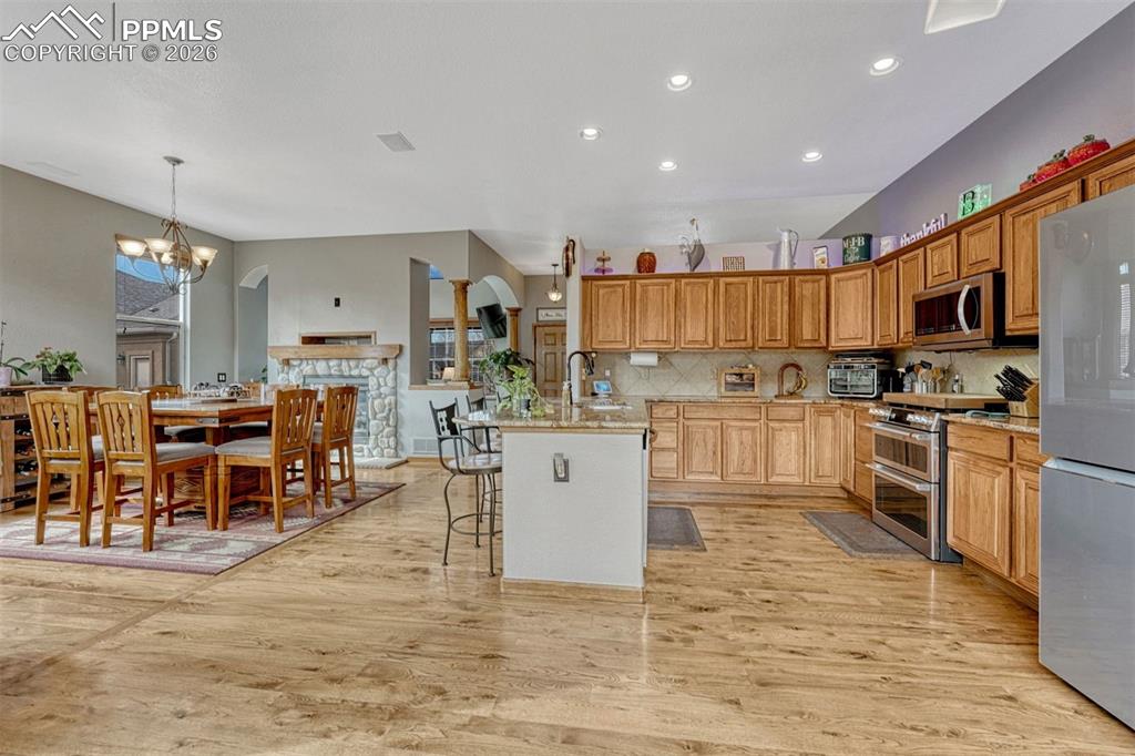 Kitchen with a kitchen bar, arched walkways, stainless steel appliances, light stone counters, and a chandelier