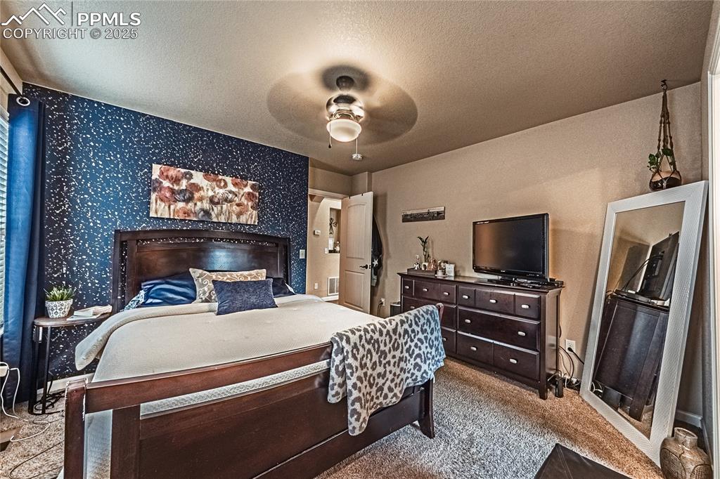 Bedroom featuring ceiling fan, light colored carpet, a textured ceiling, and wallpapered walls