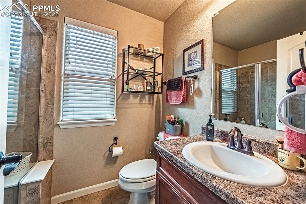 Full bathroom with a textured wall, a stall shower, vanity, tile patterned flooring, and a textured ceiling